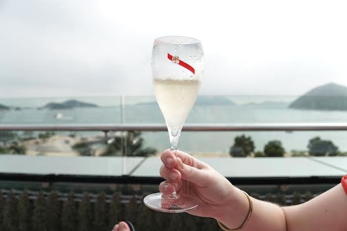 woman holding glass of champagne overlooking hong kong islands
