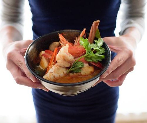 Woman holding a bowl of prawn soup