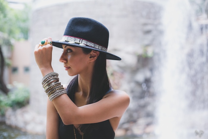 girl wearing a hat next to a waterfall