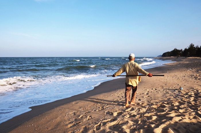 Man walking on the beach in a traditional Malay dress 