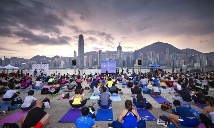 a group of people doing yoga in front of the city sky line