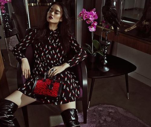 A model sat in a chair with a red handbag
