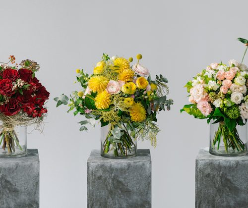 three vases of colourful flowers on stone blocks