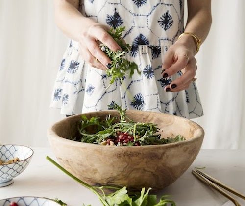 a girl in a blue dress making a salad