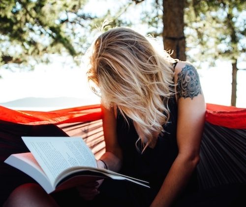 a girl reading a book in a hammock