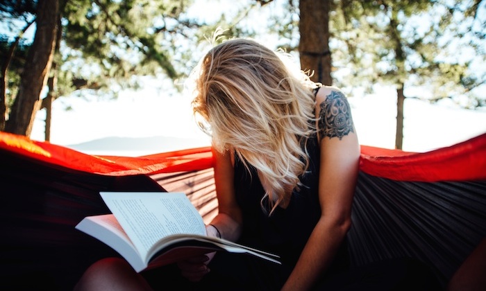 a girl reading a book in a hammock