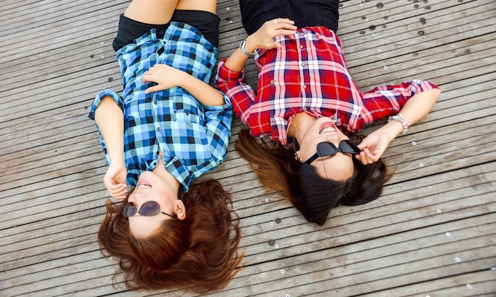 two friends lying on wooden floor wearing sunglasses