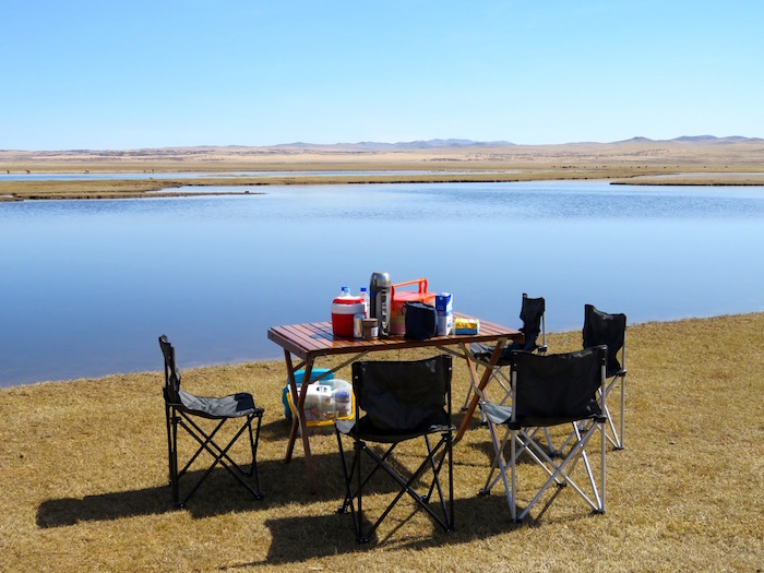 a table set up near a lake in mongolia