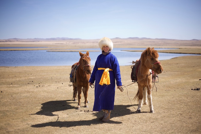 a woman in mongolia holding two horses
