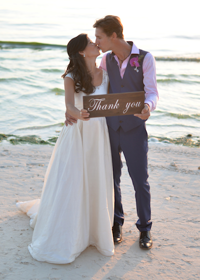 a newly wed couple holding a thank you sign