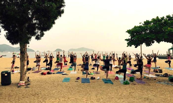 a group of people doing yoga on the beach in hong kong