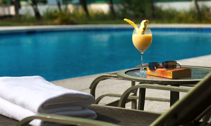 a deck chair next to the pool with a cocktail