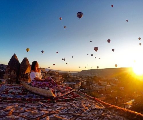 a girl looking out at hot air ballons at sunset in cappadocia turkey