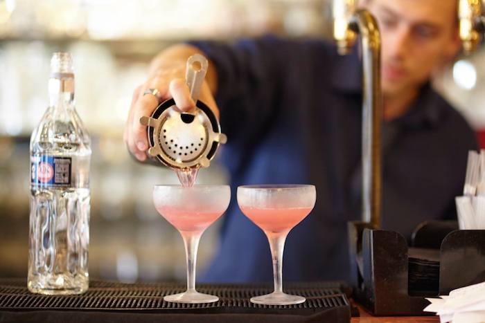 bar tender pouring pink cocktails 