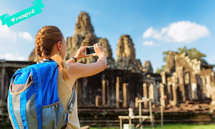 a girl taking a photograph of angkor wat in cambodia