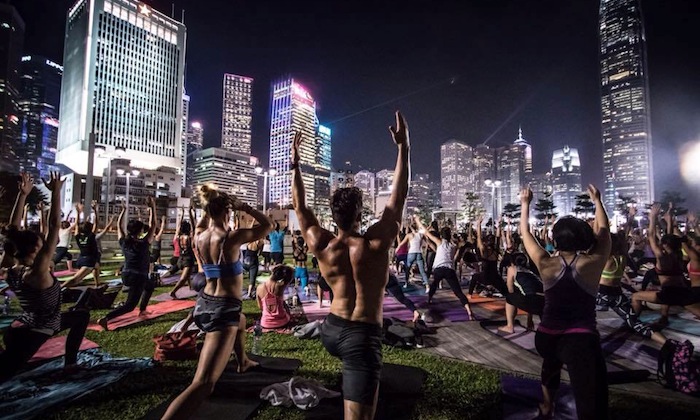 people doing yoga in front of hong kong skyline
