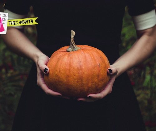 woman holding pumpkin in a black dress