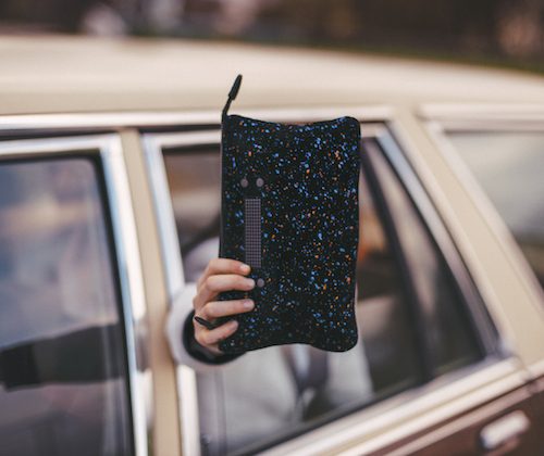 girl holding a clutch out of a car window