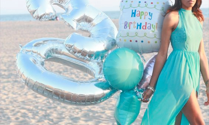 girl celebrating her 30th birthday on the beach with balloons