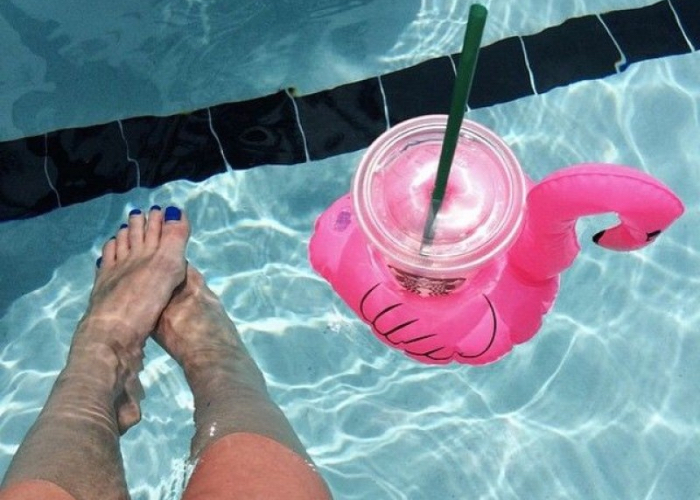 woman in pool with a drink taking a holiday