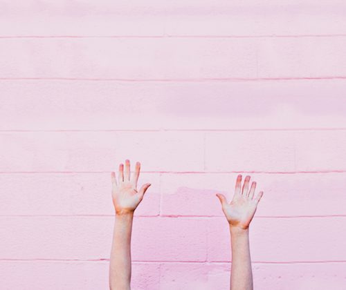 hands up against a pink wall