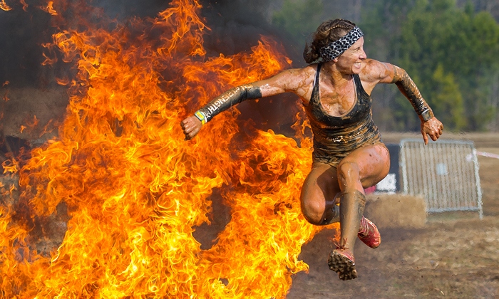 girl jumping over fire at spartan race