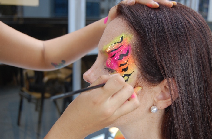 painting tiger stripes over woman's eye