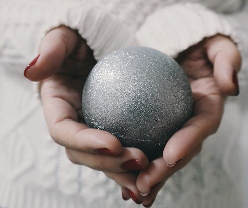 hands holding a silver bauble