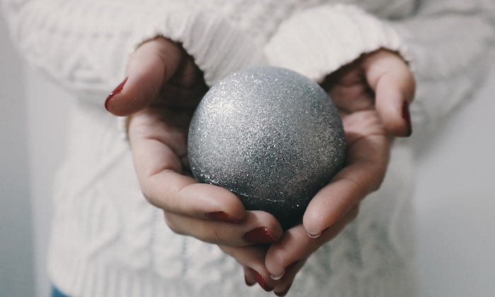 hands holding a silver bauble