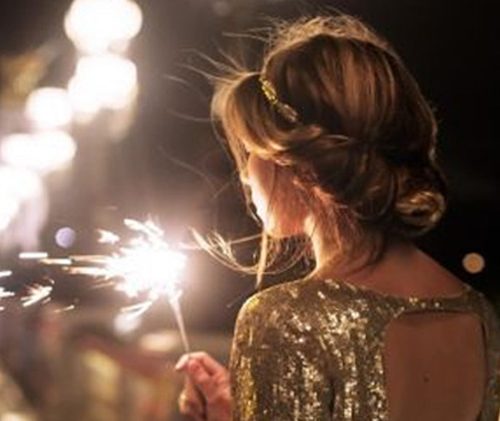 woman in a gold dress holding a sparkler