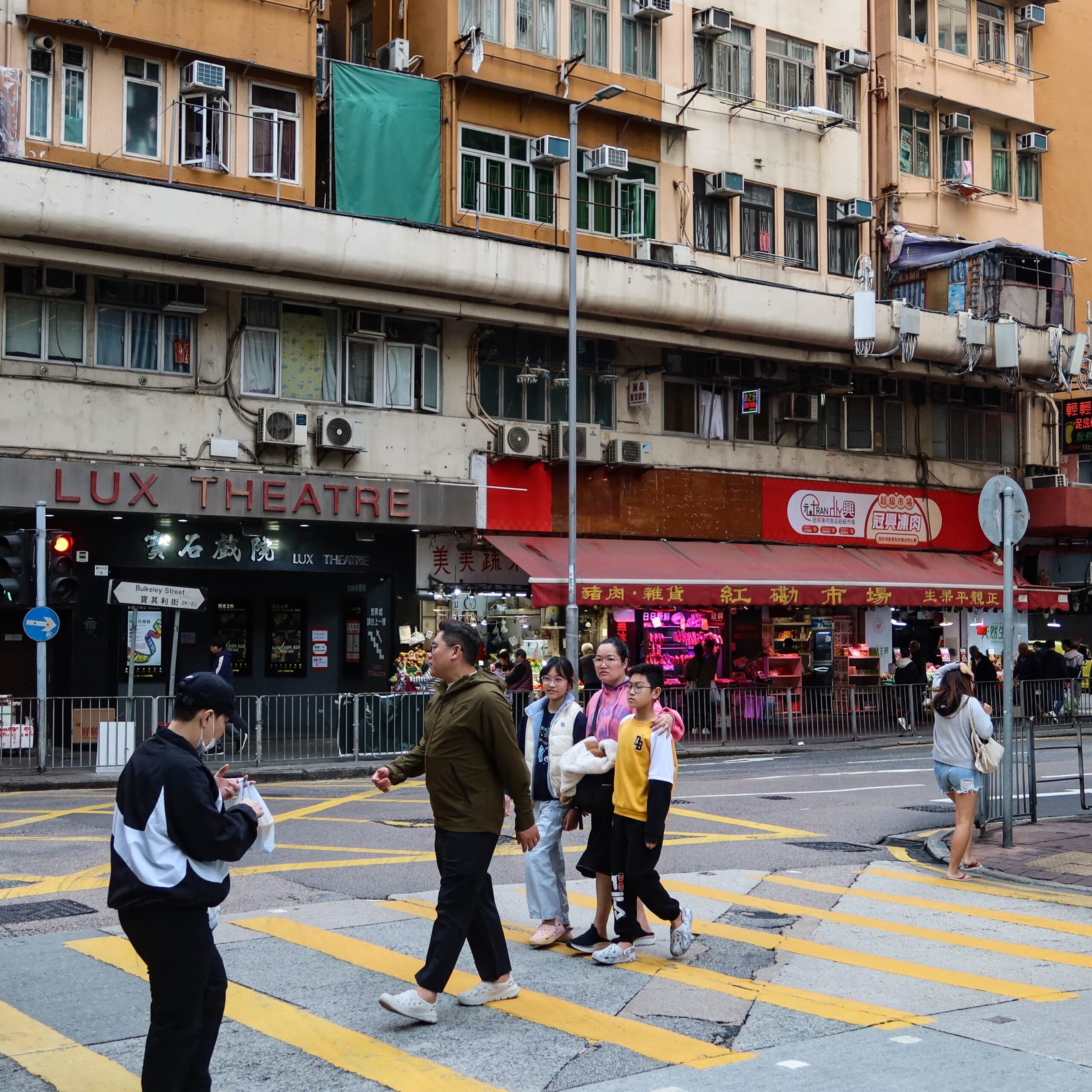 Hung Hom, Hong Kong- 5 Jan 2025: Old buildings and shops with people walking crossing the road outdoor in daytime in the old local neighbourhood community