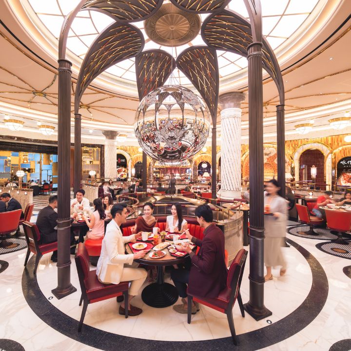 The Grand Opening of Gourmet Pavilion at Wynn Resorts Macau featuring interior of food hall with red velvet sitting and intimate tables