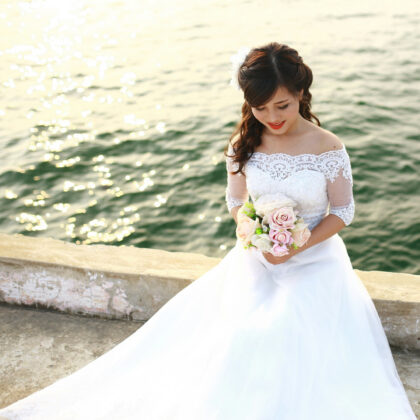 Woman wearing a wedding dress and holding a bouquet by the water in Hong Kong, where to buy wedding gowns in Hong Kong