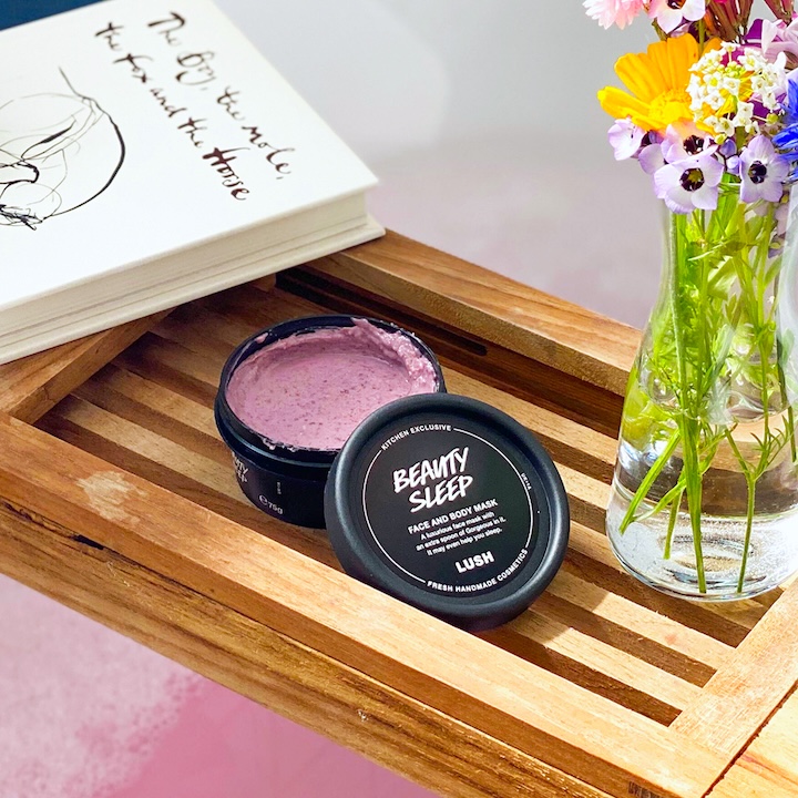 lush beauty sleep face mask beside a bathtub and bouquet of flowers