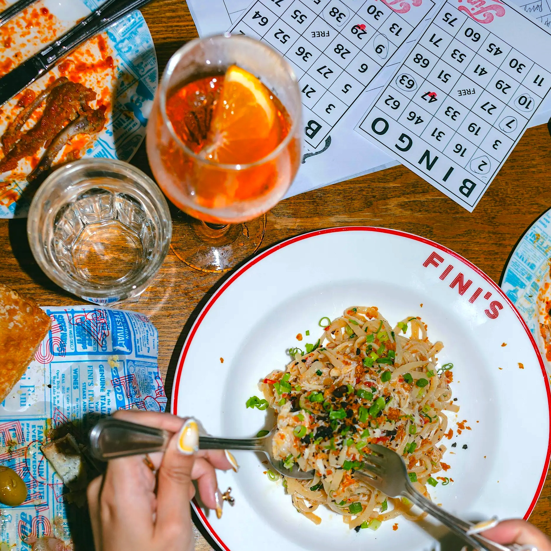 bingo cards, cocktails and pasta on a table as a part of the 'Summer Time Pops' Boozy Bingo At FINI’S Wanchai in Hong Kong in August 2026