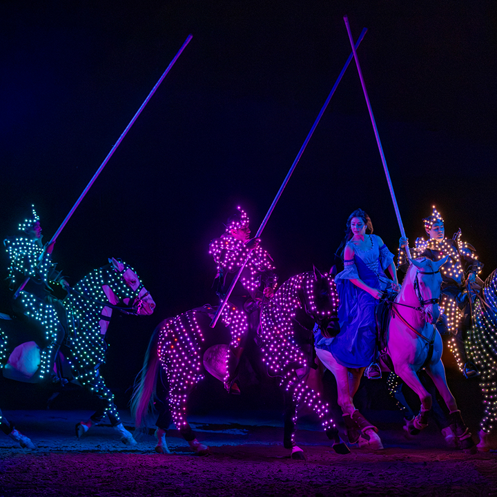 horses and their riders lit up on a dark stage during the CAVALLUNA: Gate To The Otherworld show