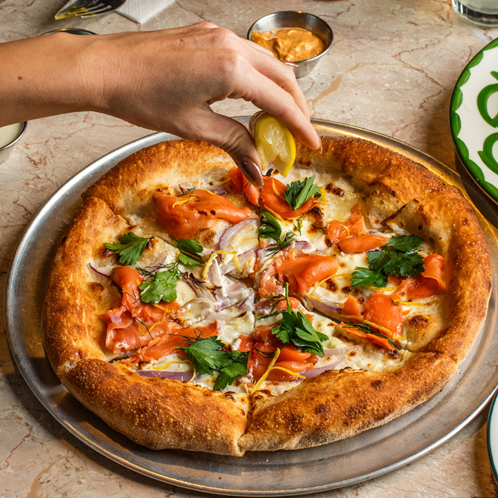 Squeezing lemon on a salmon pizza at Emmer Pizza in Hong Kong