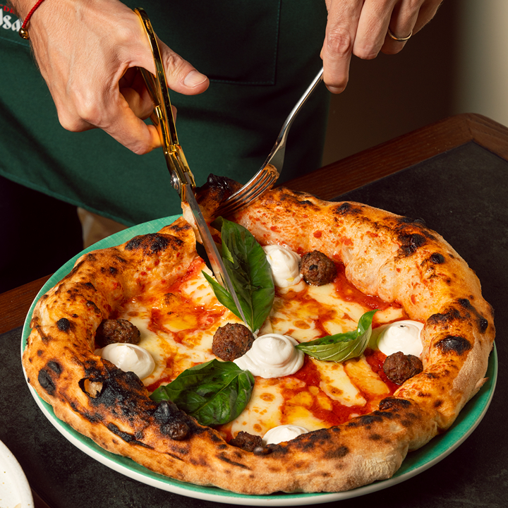 Cutting up a pizza at Vincenzo Capuano in Wan Chai with golden scissors as part of the contemporary Neapolitan pizza tradition with Nuvola dough