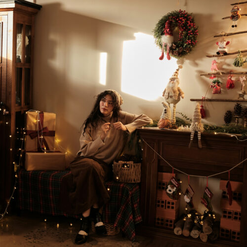 Woman at home surrounded by Christmas decorations in Hong Kong, christmas presents, wreath, stockings, christmas lights and more