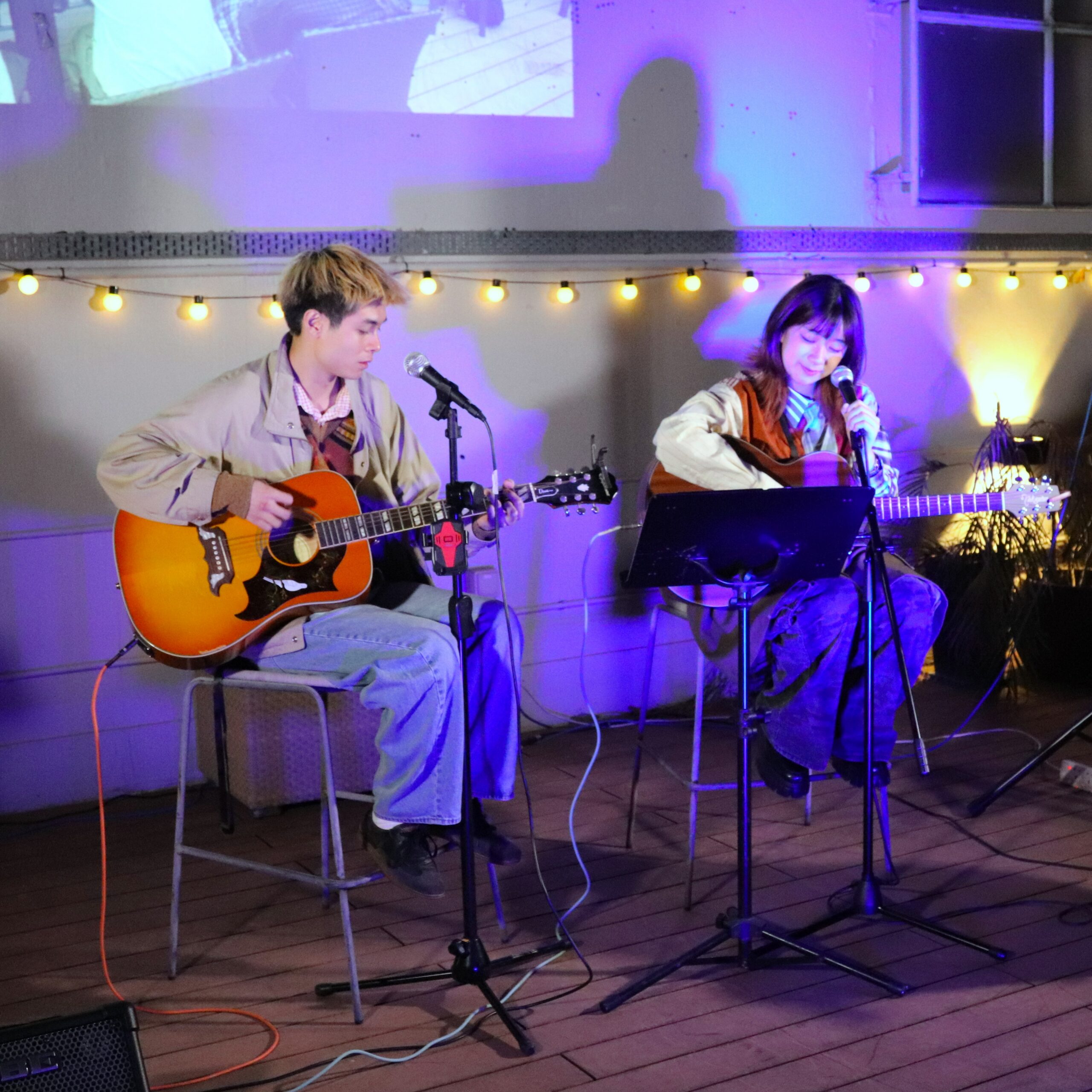 man and woman performing music on guitars in The Hive's backyard for Live At The Hive 2026 in november in hong kong